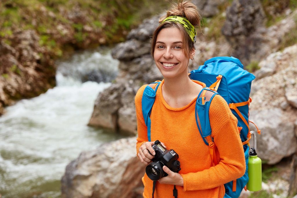 smiling woman with backpack exploring mountains on a luxury adventure tour in India